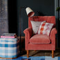  Brass Waxed Floor Lamp with To The Point Paper Empire Lamp Shade in Soft White with Peacock Blue Trim, next to an Ottoman with books and Armchair With Cushions - NiX by Nicola Harding & Co. 