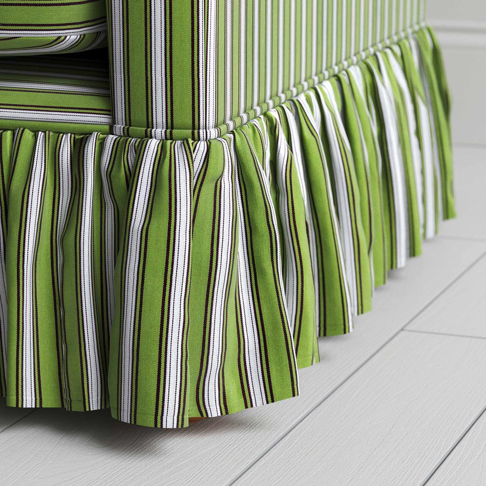 Detailed view of a fashionable green and white striped skirt on sofa.
