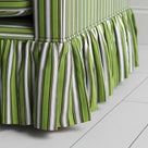 Detailed view of a fashionable green and white striped skirt on sofa.