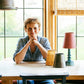 A woman sitting at a table with a lamp and a lampshade, creating a cozy and well-lit ambiance.