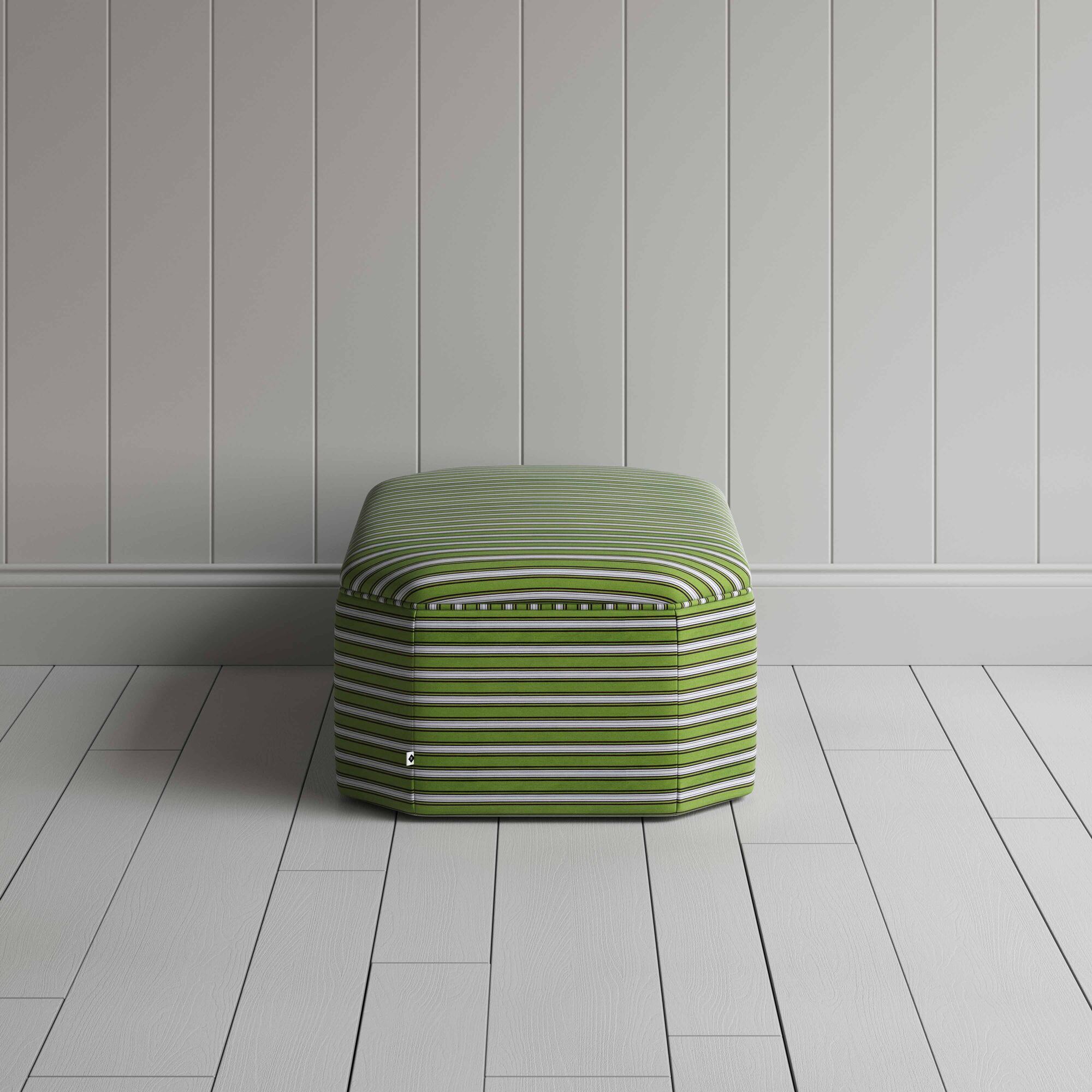  A green and white striped ottoman on a white floor, adding a touch of color and pattern to the room. 