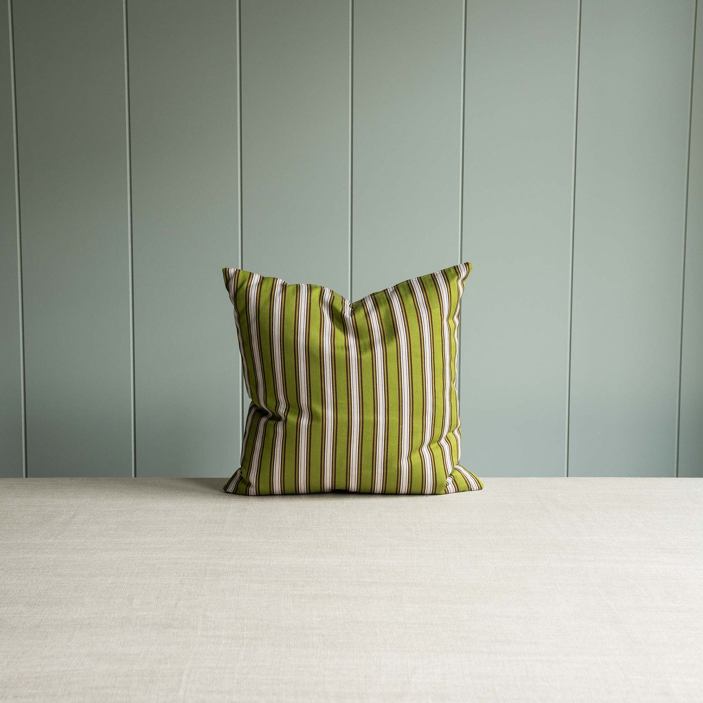 Green and white stripped pillow against the gray wall.