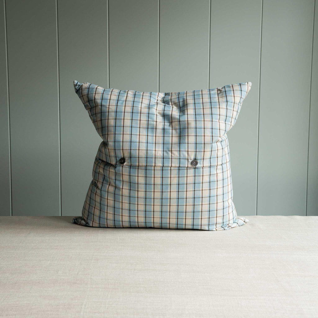  Blue pillow with white plaid pattern on table. 