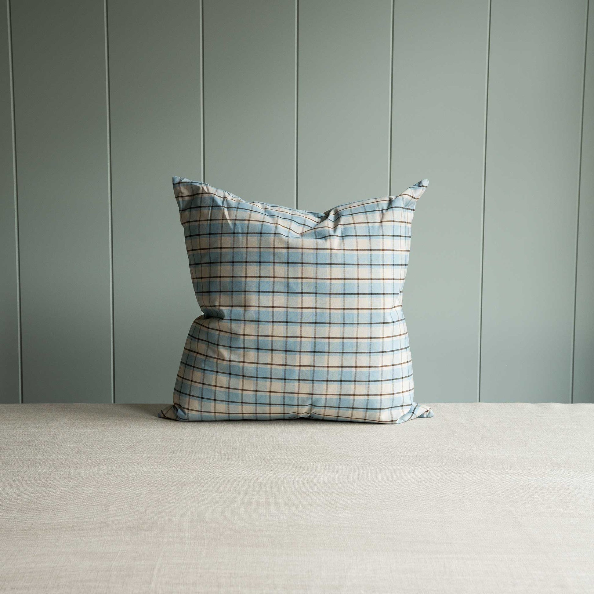 A blue and white plaid pillow resting on a table, adding a touch of pattern and color to the space.