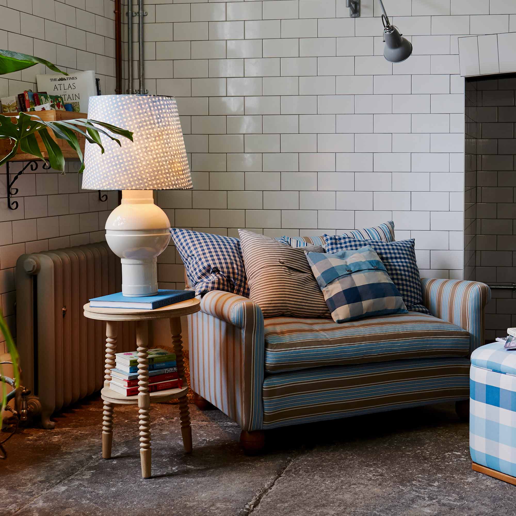  Orb Ceramic Table Lamp Base in Warm White, With Humbug Straight Empire Batik Paper Lamp Shade in Dotty Sky Blue, On a Side table Next to a Loveseat With Cushions - Nicola Harding 